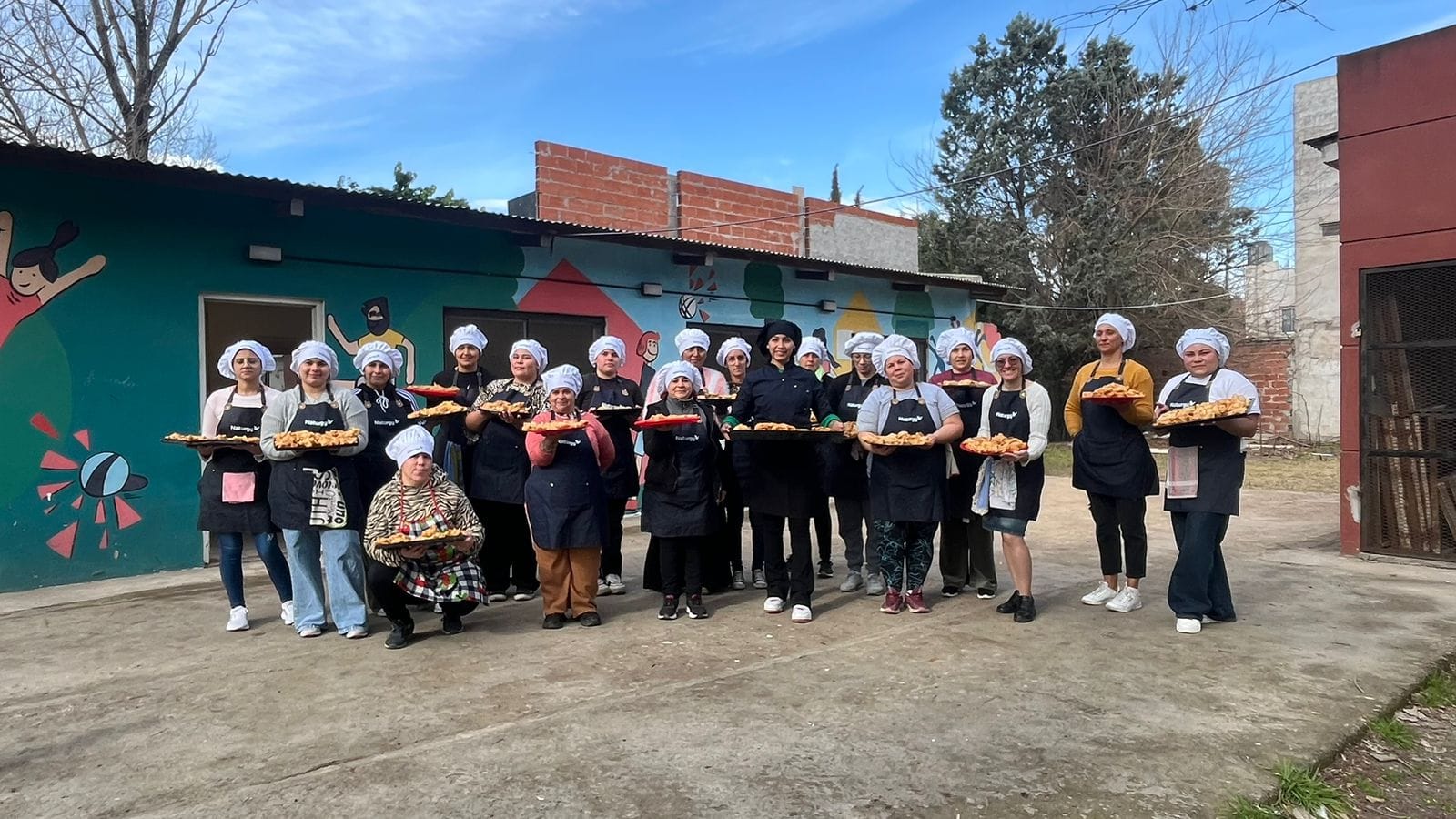El espíritu de la independencia argentina se sintió con un sabor muy especial en el barrio Cascallares de Moreno. En una emotiva jornada que se ha convertido en tradición, Naturgy Argentina, en alianza con la Asociación Civil Siloé, celebró el 9 de Julio agasajando a los vecinos con delicias caseras . Los protagonistas de esta celebración fueron los mismos participantes de Siloé en el programa "Energía del Sabor" de Naturgy Argentina. Esta acción, que se repite año tras año en una fecha tan significativa es un reflejo del impacto transformador del programa. “Esta iniciativa fue la primera experiencia comunitaria de la cohorte 2025 y se llevó a cabo el mismo 9 de julio con el objetivo de hacer la práctica inicial de producción en serie. Resultó sumamente positivo generar este espacio, que no solo incluye aprendizaje sino un servicio para la comunidad de Cascallares. Fue muy emotivo el contacto con los vecinos, disfrutamos mucho la experiencia”, aseguró Lucía Orcaizaguirre, coordinadora de Siloé del programa Energía del Sabor. "Energía del Sabor" es un programa que crea espacios de aprendizaje y jerarquización de oficios gastronómicos, proporcionando a sus participantes las herramientas necesarias para lograr una inserción laboral genuina y sustentable. El objetivo central es claro: brindar oportunidades concretas de desarrollo e independencia económica a quienes se capacitan. La iniciativa no solo se desarrolla en Buenos Aires, sino que también tiene ediciones activas en la Región NOA, expandiendo su impacto positivo a diversas comunidades del país. En la provincia de Buenos Aires, el programa cuenta con el valioso apoyo y la colaboración de entidades clave como la UTHGRA Morón (Unión de Trabajadores del Turismo, Hoteleros y Gastronómicos de la República Argentina), la Fundación Siloé del partido de Moreno y la Fundación Peregrina del barrio Las Tunas, en el partido de Tigre. La actividad es abierta a la comunidad. Esta jornada en Cascallares es un claro ejemplo de cómo la colaboración entre el sector privado y organizaciones civiles puede generar un impacto social positivo en las comunidades. Podés conocer más de esta experiencia haciendo click acá.